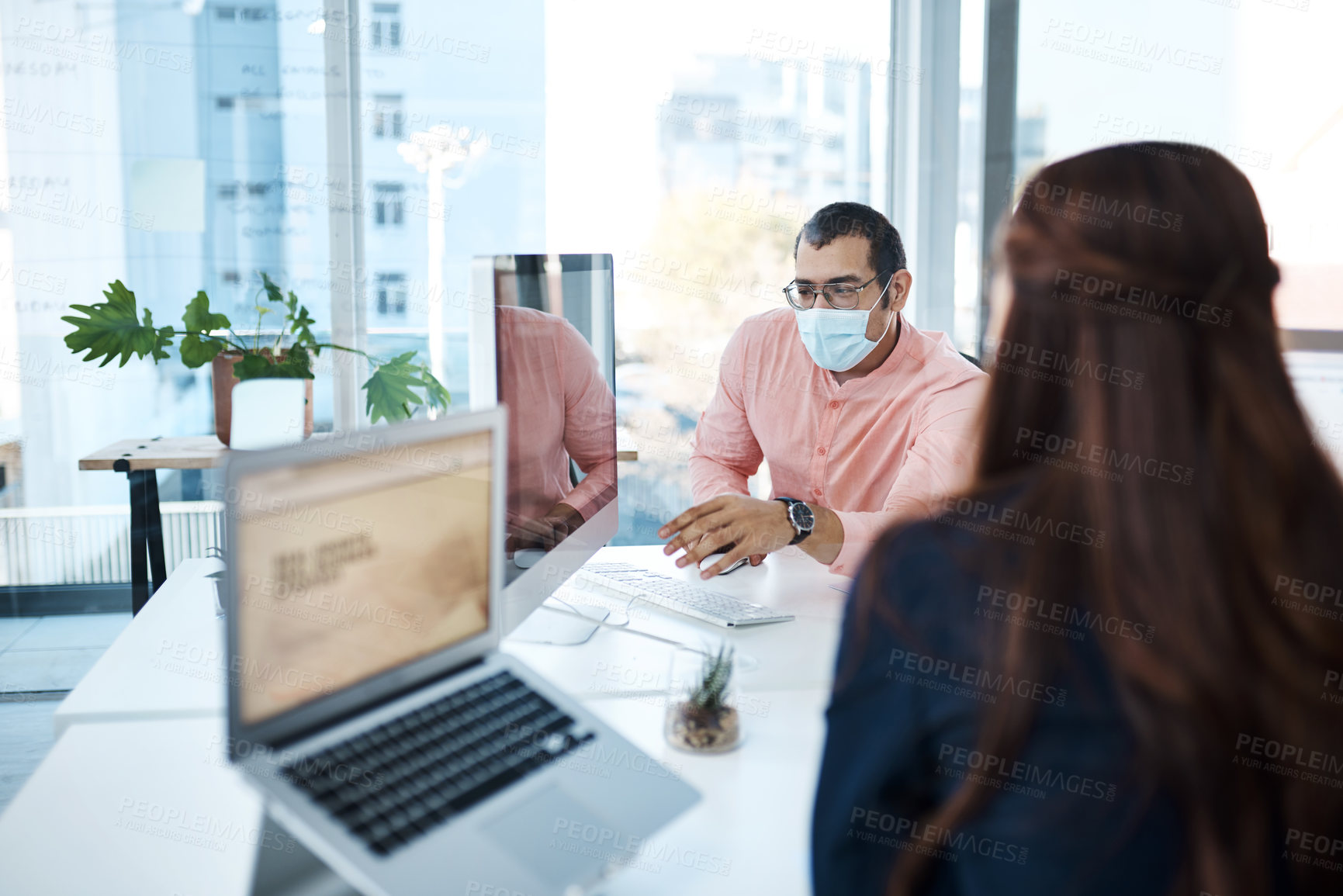 Buy stock photo Shot of two businesspeople wearing face masks while working together in an office