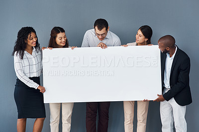 Buy stock photo Portrait of a group of businesspeople holding a black poster while standing against a grey background
