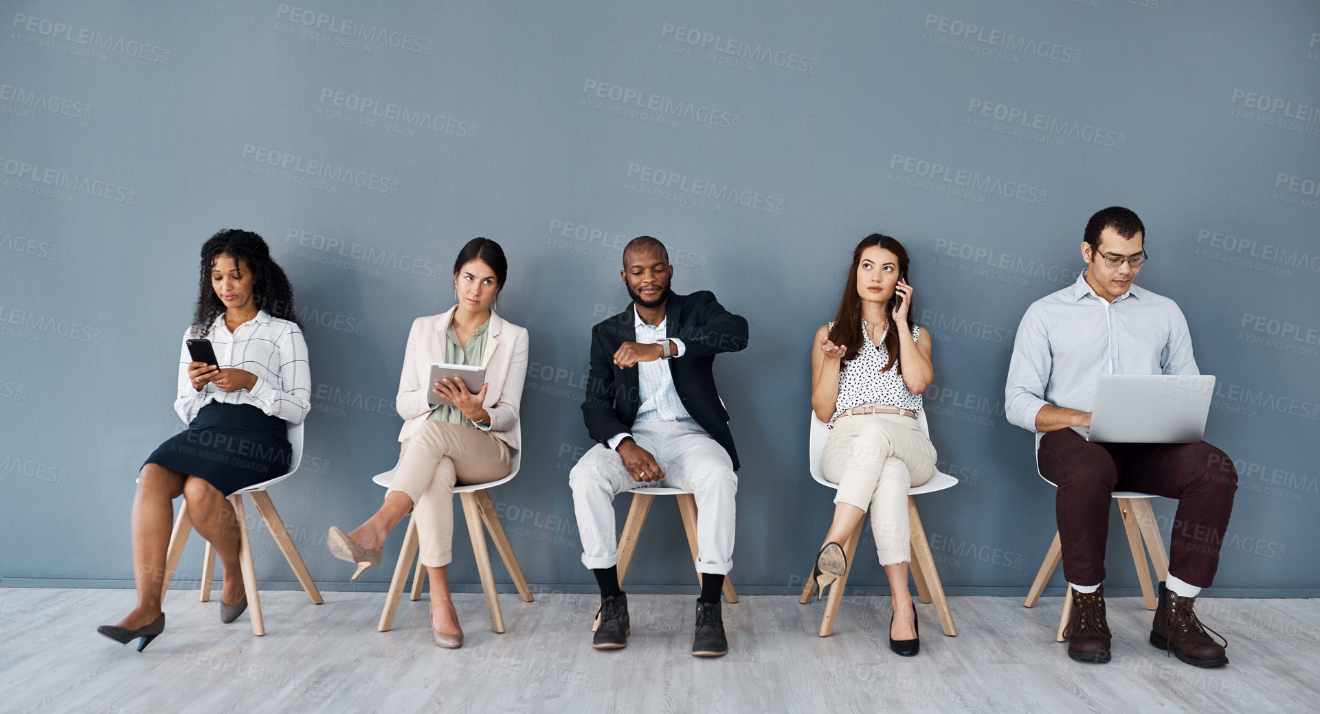 Buy stock photo Shot of a group of businesspeople using digital devices while sitting in line against a grey background