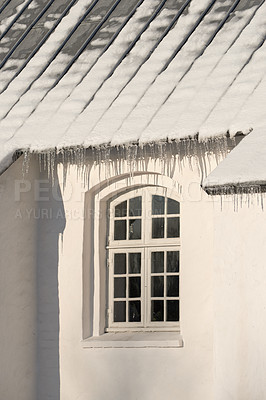 Buy stock photo Empty building with ice damming on the roof on a cold winter day. The exterior of a home or house with snow on the rooftop on a sunny afternoon. Frost on a historic church in a village