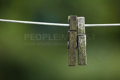Buy stock photo Old pegs on a clothesline outdoors against a blurred background with copy space. Details of two weathered wooden clothespins used as household objects for hanging and drying clothing on laundry day