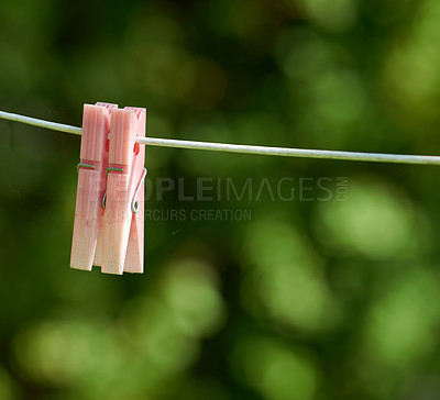 Buy stock photo Closeup of washing line with pins hanging outside against a bokeh green background. Empty clothesline with plastic clothes peg in a backyard on laundry day with copy space for domestic chores 