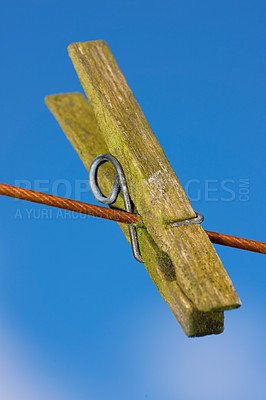 Buy stock photo Closeup of one clothes peg hanging on an empty laundry line outside in a garden. A clothing pin is a tool to hang up clothes outside to dry while doing housework and chores. Zoom of a wooden peg