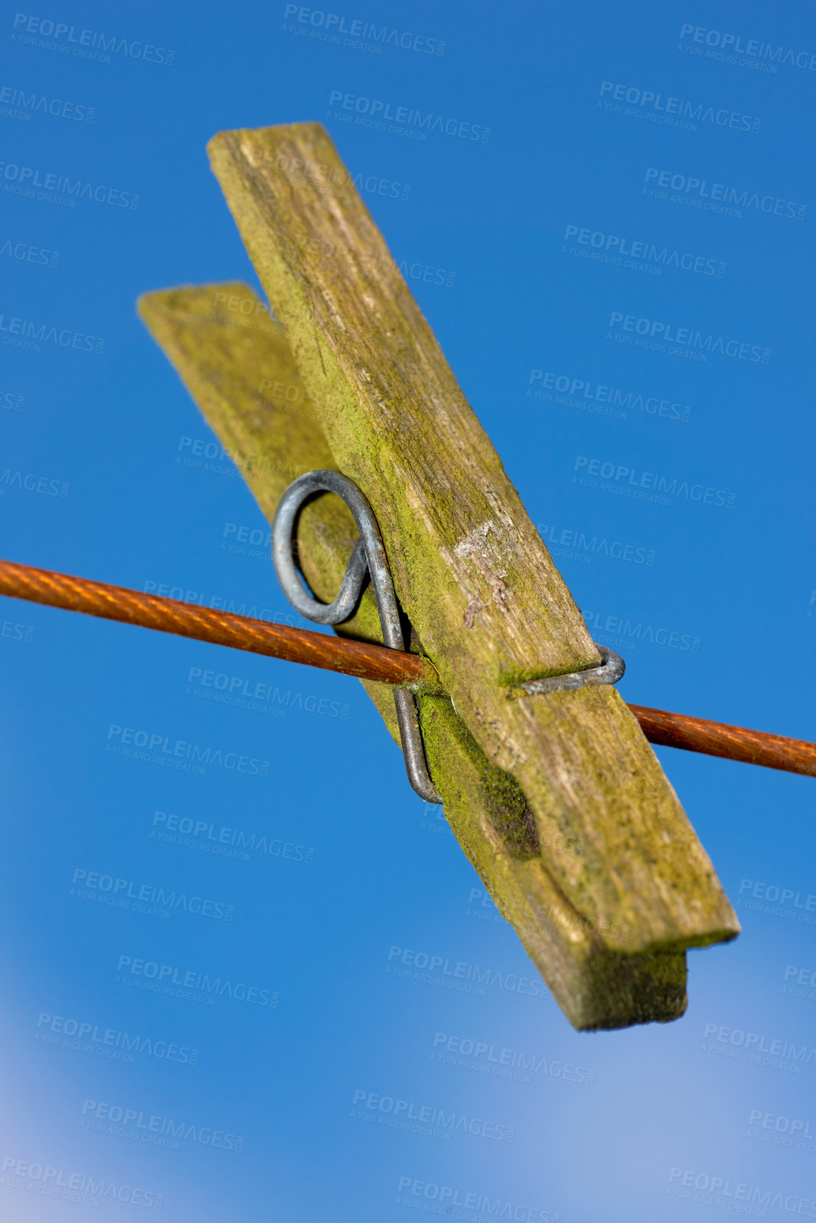 Buy stock photo Closeup of one clothes peg hanging on an empty laundry line outside in a garden. A clothing pin is a tool to hang up clothes outside to dry while doing housework and chores. Zoom of a wooden peg