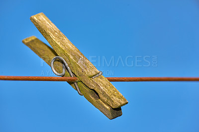 Buy stock photo An old peg on a clothing line outdoors against blue sky copy space background. Closeup details a weathered wooden clothespin used as household objects for a tradition clothing drying on laundry day