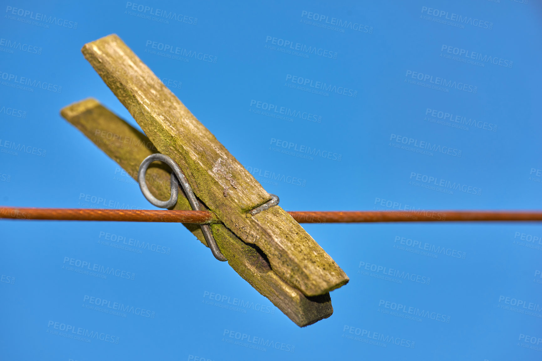 Buy stock photo An old peg on a clothing line outdoors against blue sky copy space background. Closeup details a weathered wooden clothespin used as household objects for a tradition clothing drying on laundry day