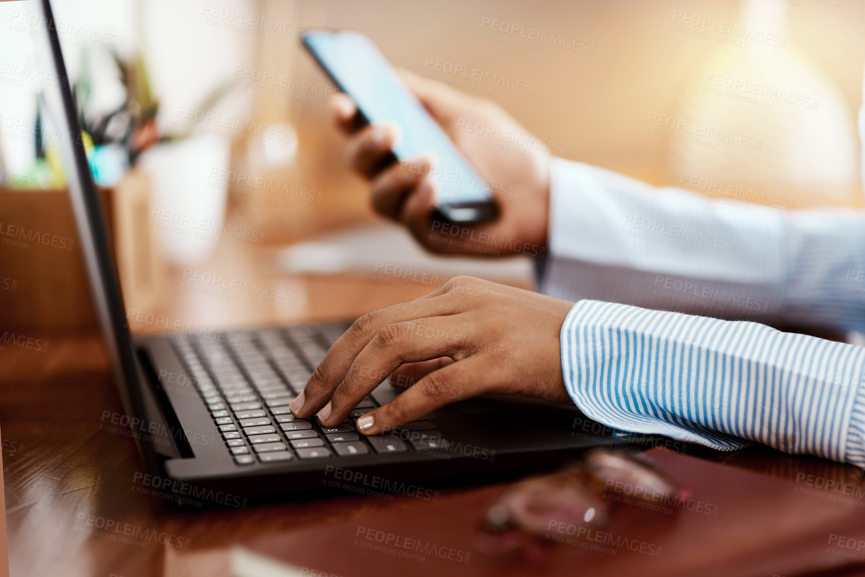 Buy stock photo Cropped shot of a businesswoman using a laptop and smartphone at her desk