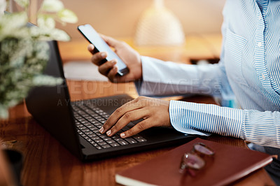 Buy stock photo Cropped shot of a businesswoman using a laptop and smartphone at her desk