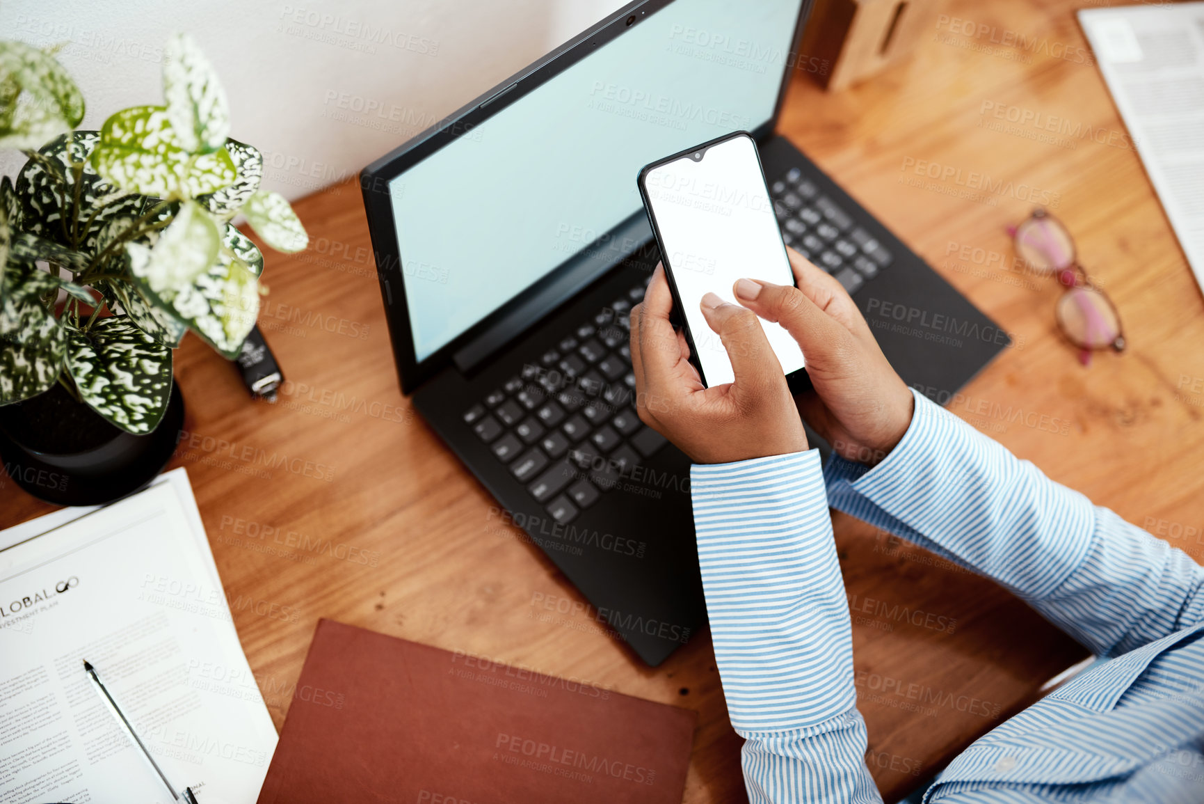 Buy stock photo Cropped shot of a businesswoman using a laptop and smartphone at her desk