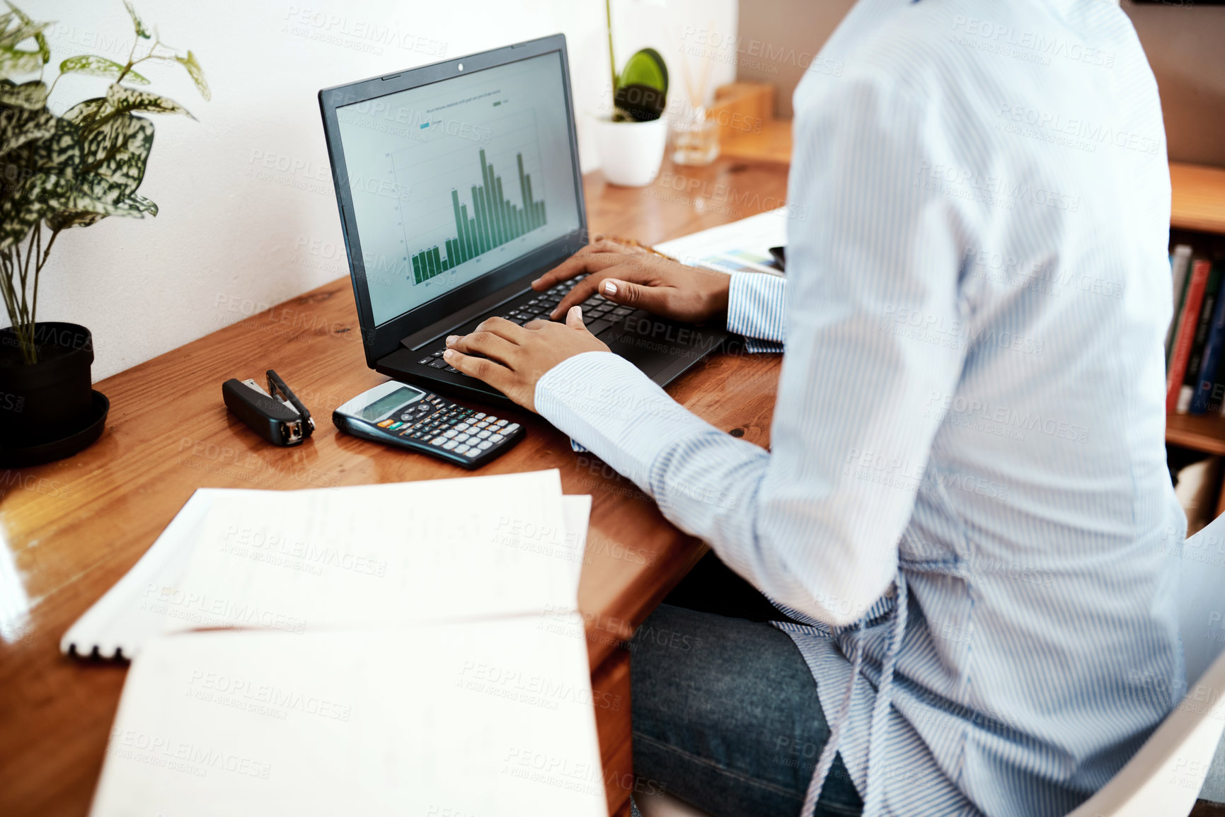 Buy stock photo Cropped shot of a businesswoman using a laptop while analysing financial data at her desk