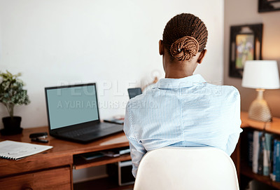 Buy stock photo Rearview shot of a young businesswoman using a smartphone while working from home