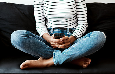 Buy stock photo Cropped shot of a woman using a smartphone on the sofa at home