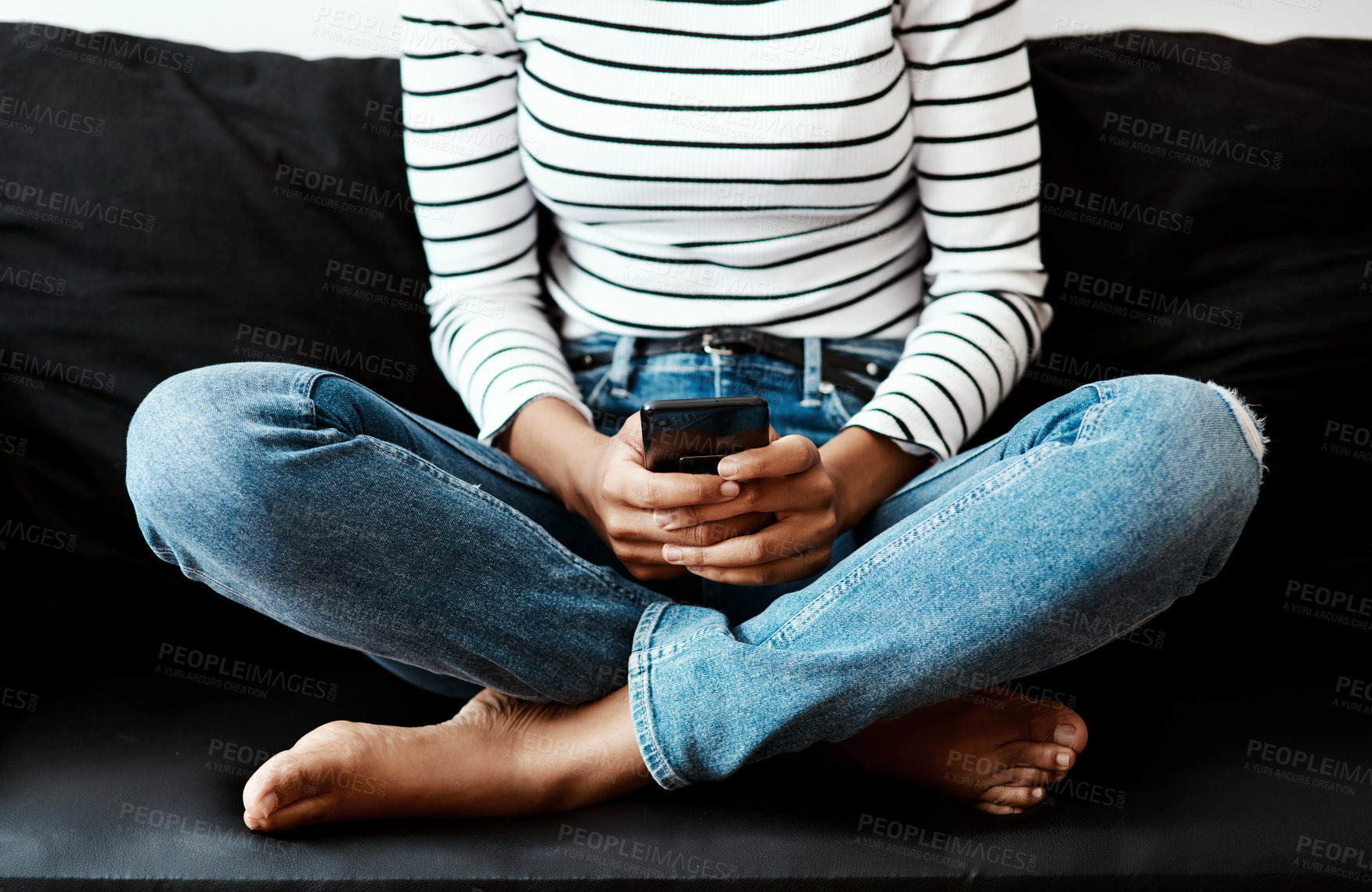 Buy stock photo Cropped shot of a woman using a smartphone on the sofa at home
