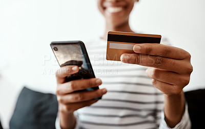 Buy stock photo Cropped shot of a woman using a smartphone and credit card on the sofa at home