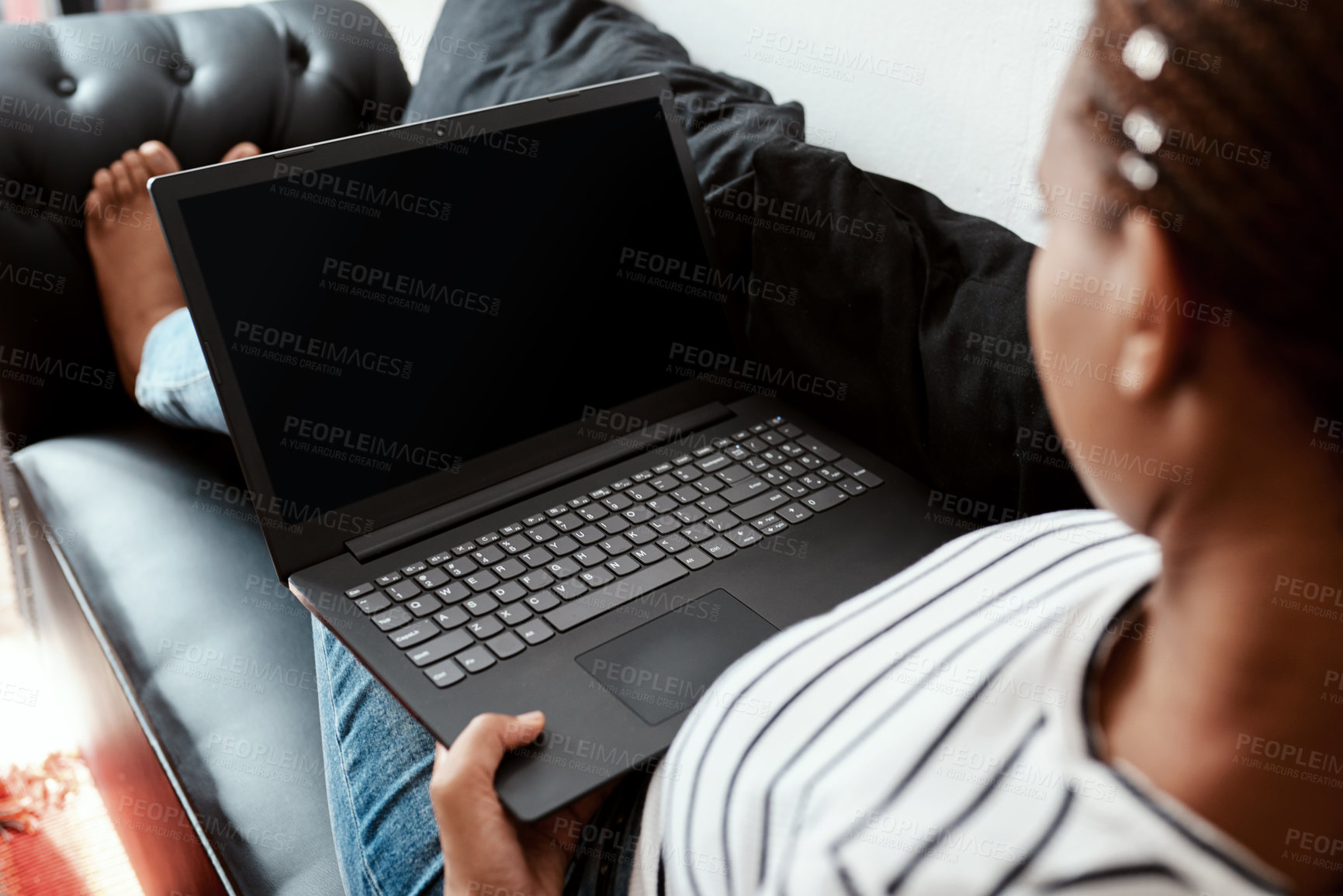 Buy stock photo Cropped shot of a woman using a laptop on the sofa at home