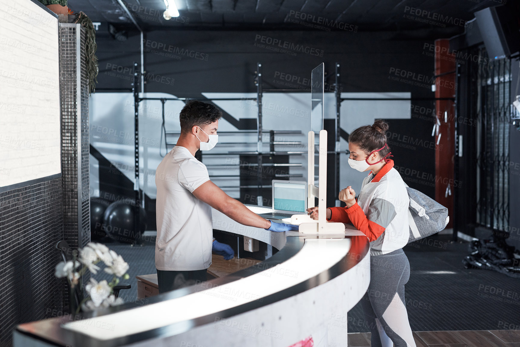 Buy stock photo Shot of a young woman filling in paperwork at the reception desk of a gym