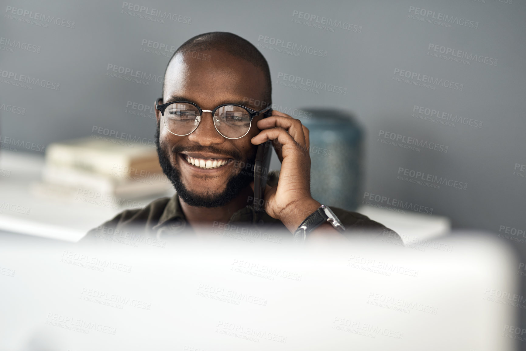 Buy stock photo Shot of a young businessman using a smartphone and computer in a modern office