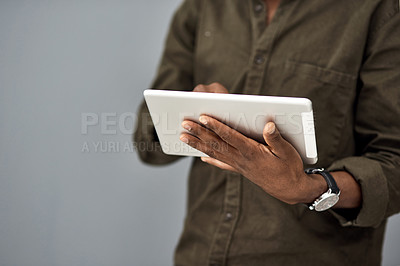 Buy stock photo Studio shot of an unrecognisable businessman using a digital tablet against a gray background