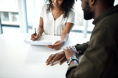 Buy stock photo Shot of a young businessman and businesswoman filling out paperwork during a meeting in a modern office