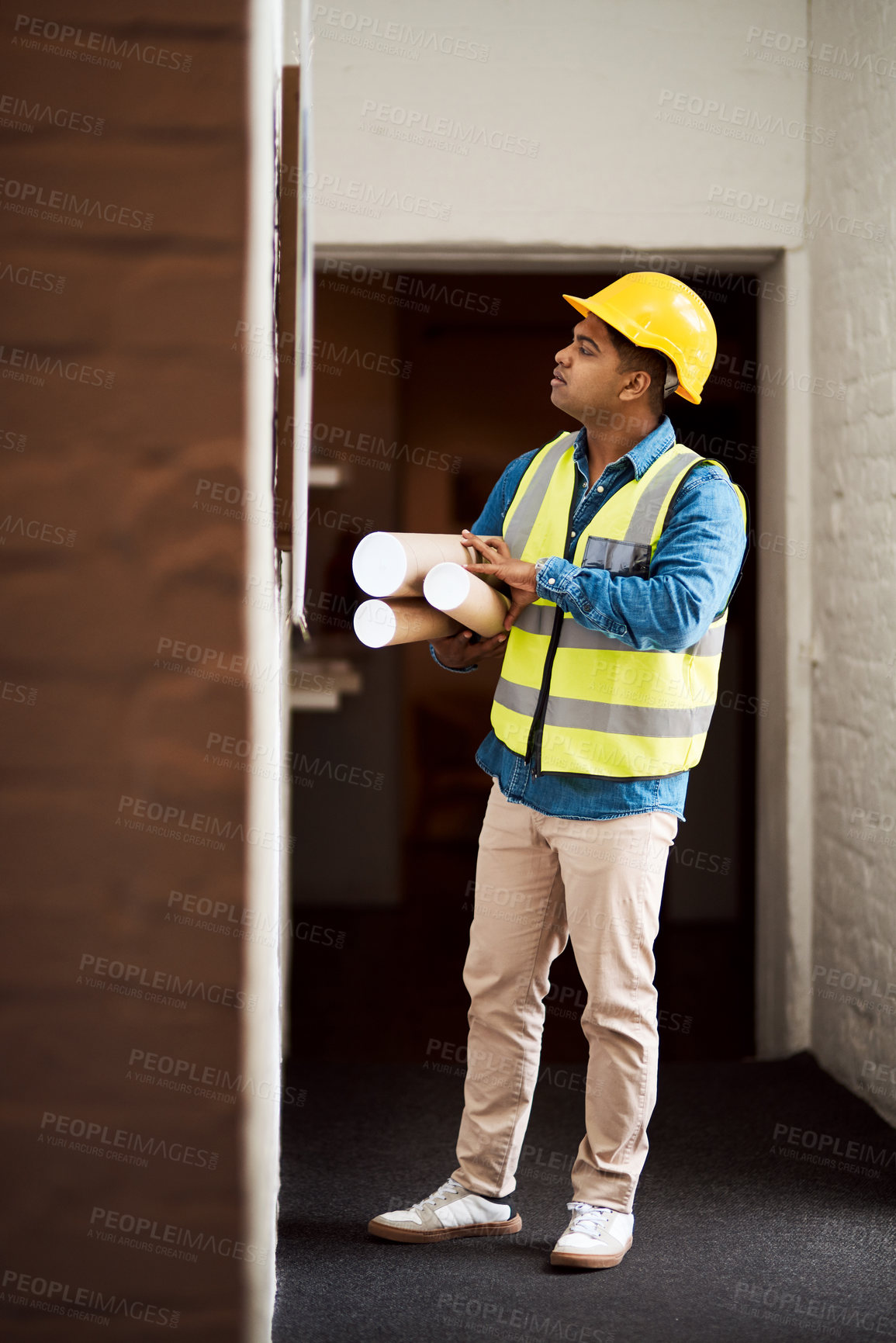 Buy stock photo Shot of a young engineer reading something on a wall