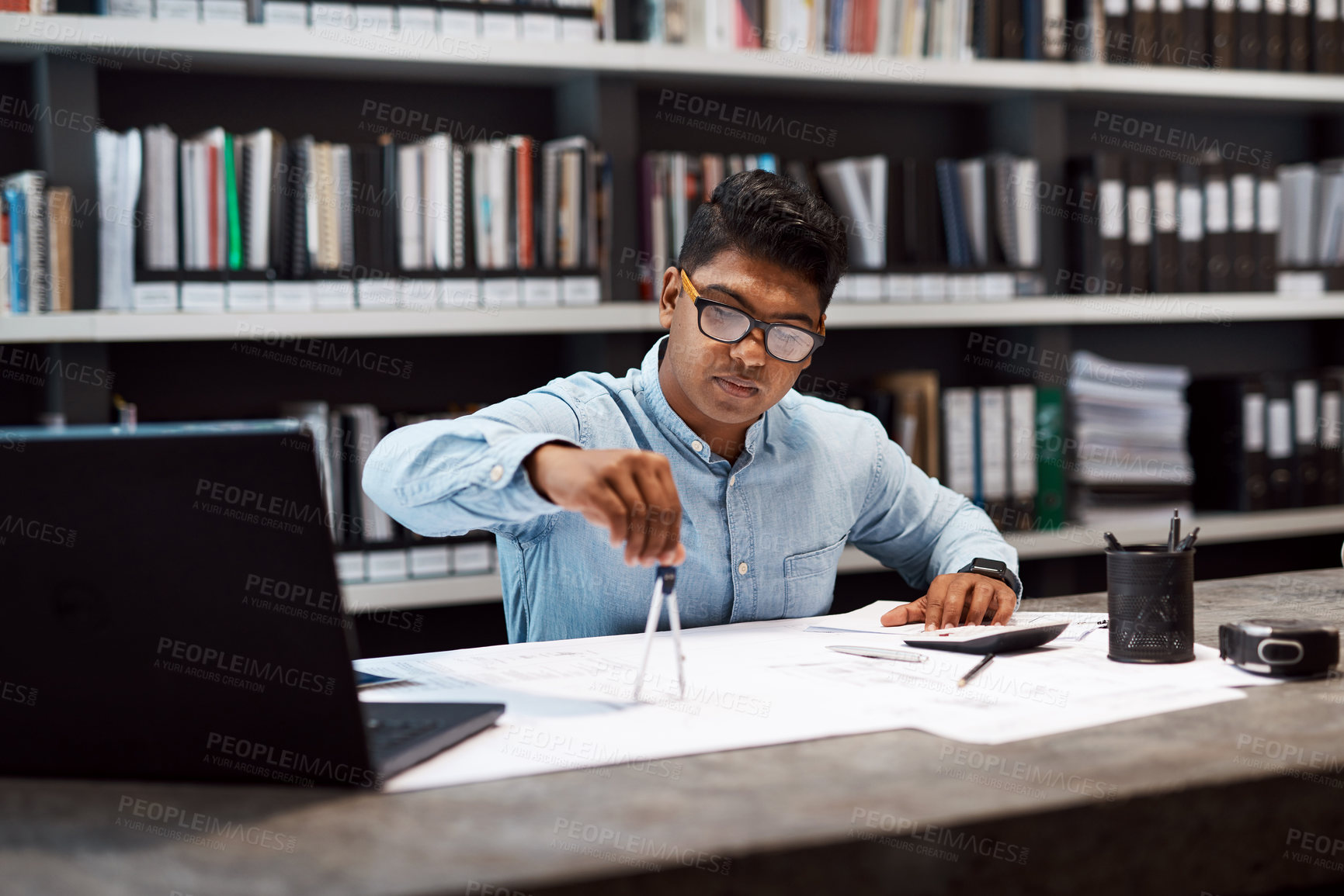 Buy stock photo Shot of a young architect using a compass to draw a building plan