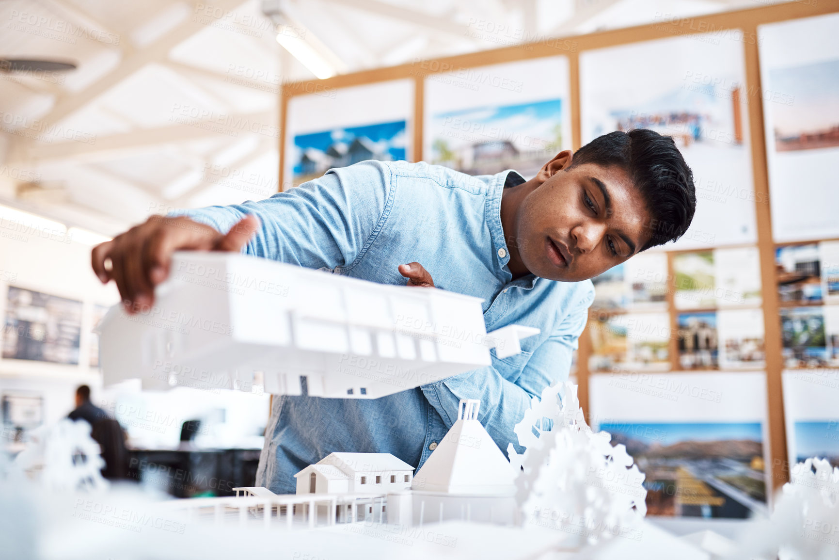 Buy stock photo Shot of a young architect designing a building model in a modern office