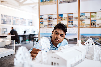 Buy stock photo Shot of a young architect designing a building model in a modern office