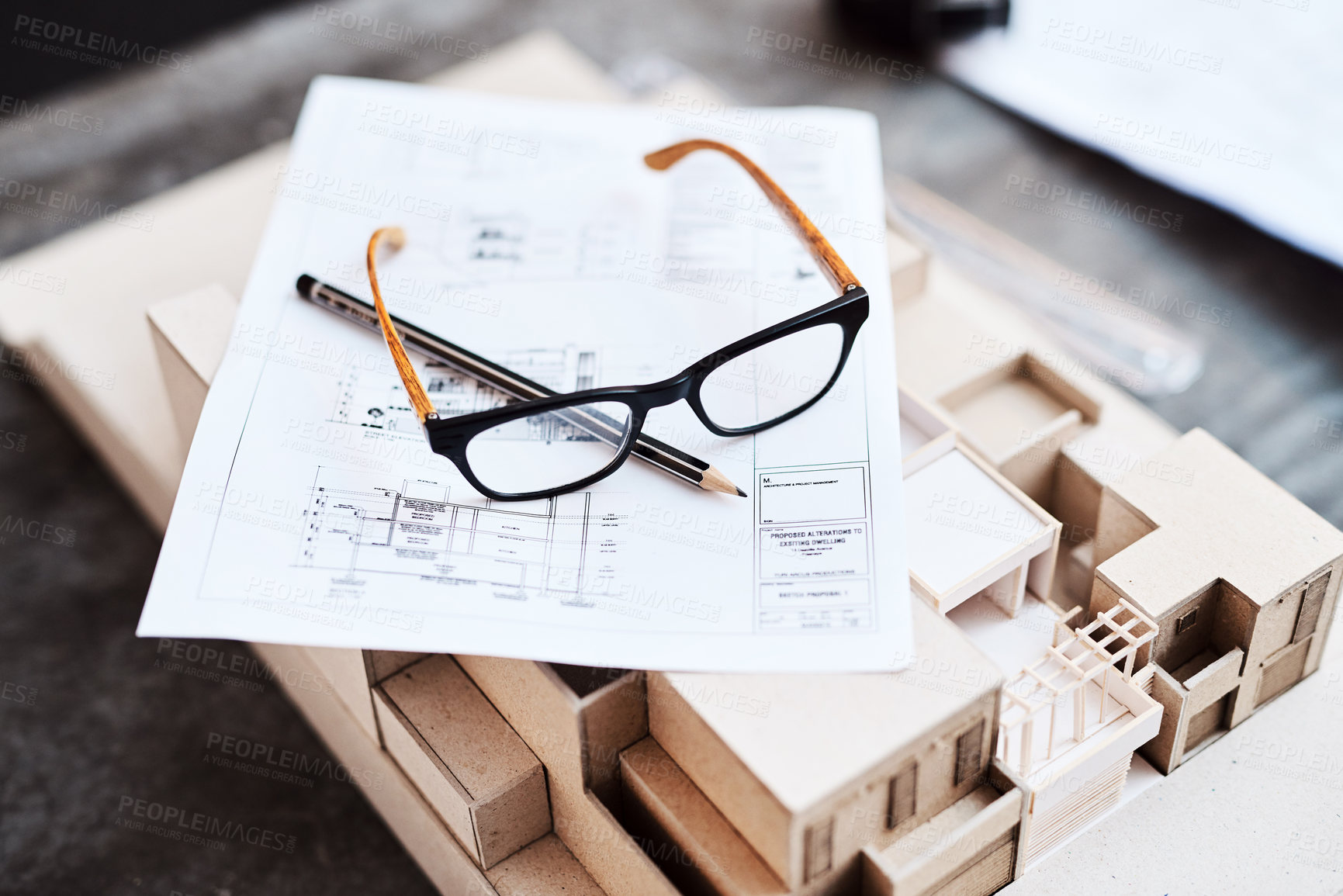 Buy stock photo Shot of glasses, a pencil, blueprint and building model on a desk in an office