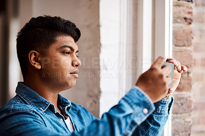 Buy stock photo Shot of a young businessman taking a picture from a window at work