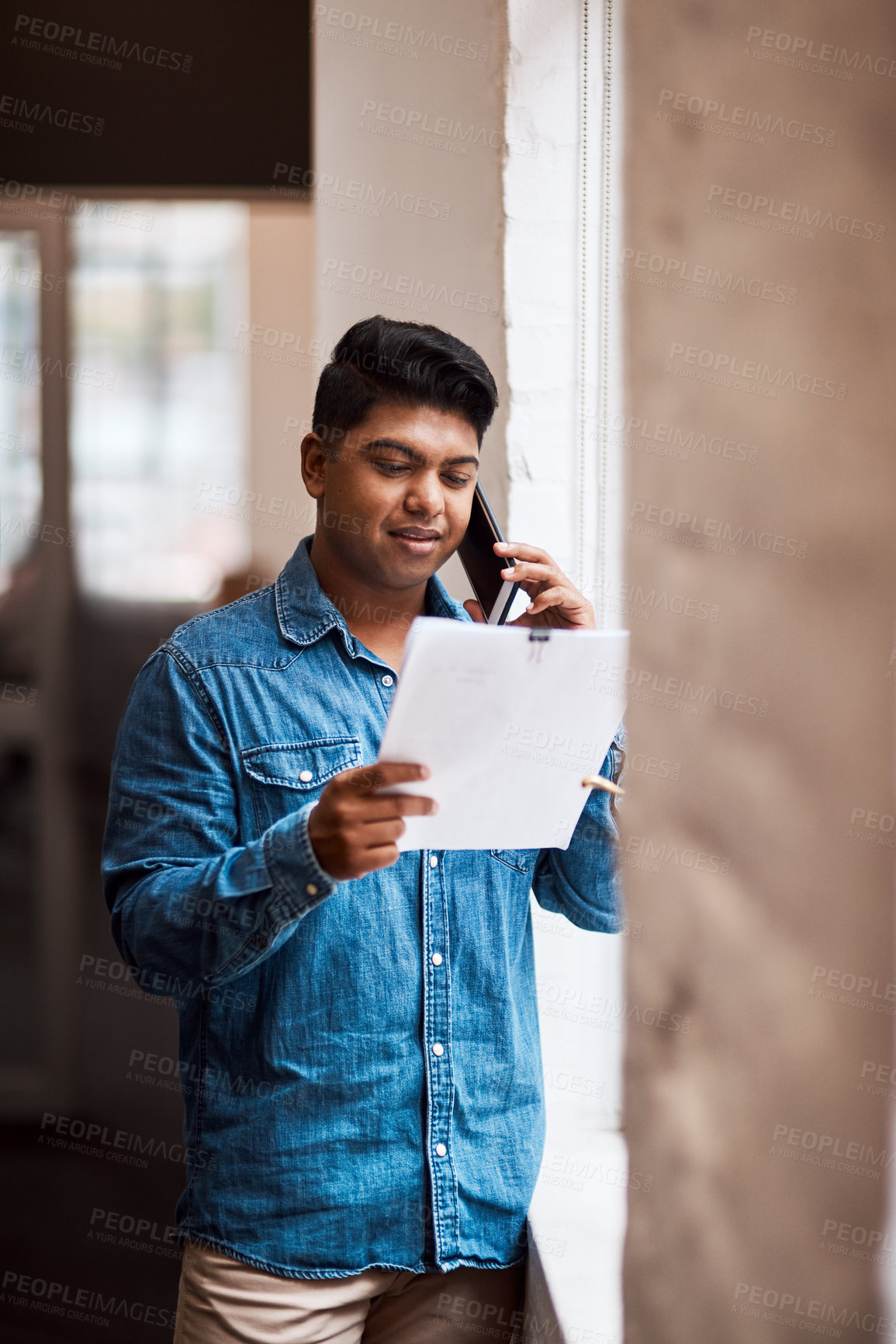 Buy stock photo Shot of a man talking on his cellphone while looking at paperwork
