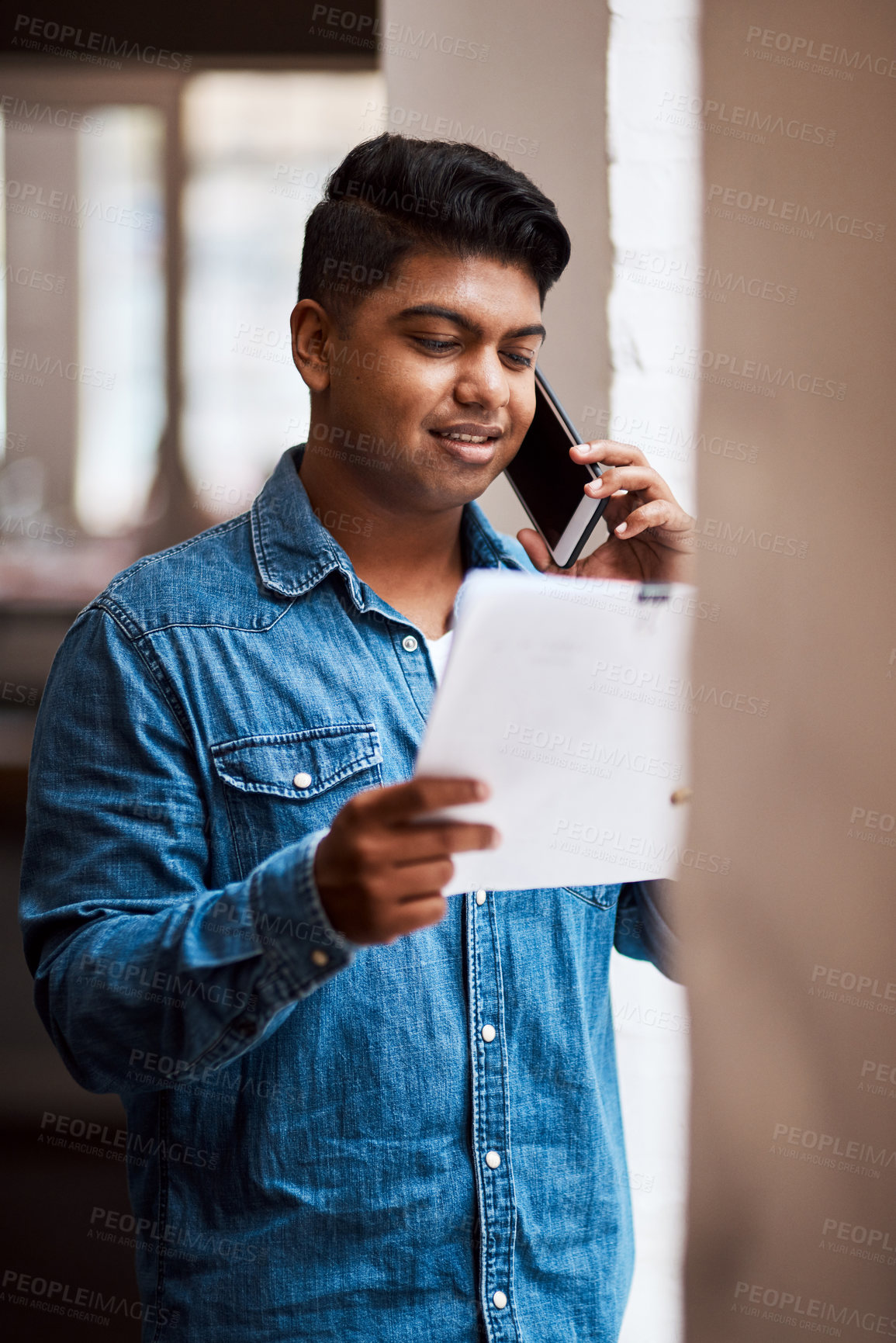 Buy stock photo Shot of a man talking on his cellphone while looking at paperwork