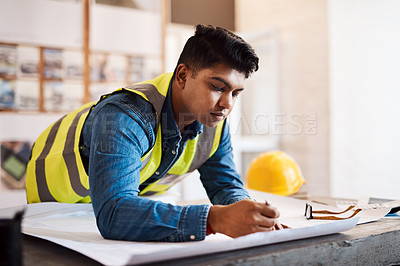 Buy stock photo Shot of a young architect drawing up a building plan in his office