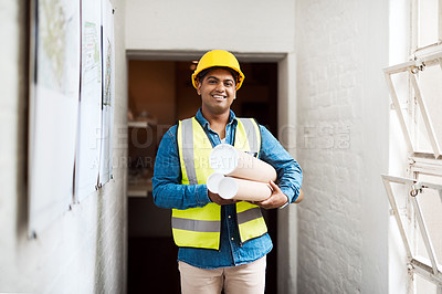 Buy stock photo Shot of a young engineer holding blueprints on a construction site