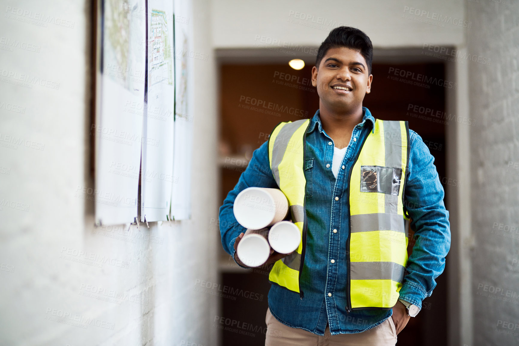 Buy stock photo Shot of a young engineer holding blueprints on a construction site