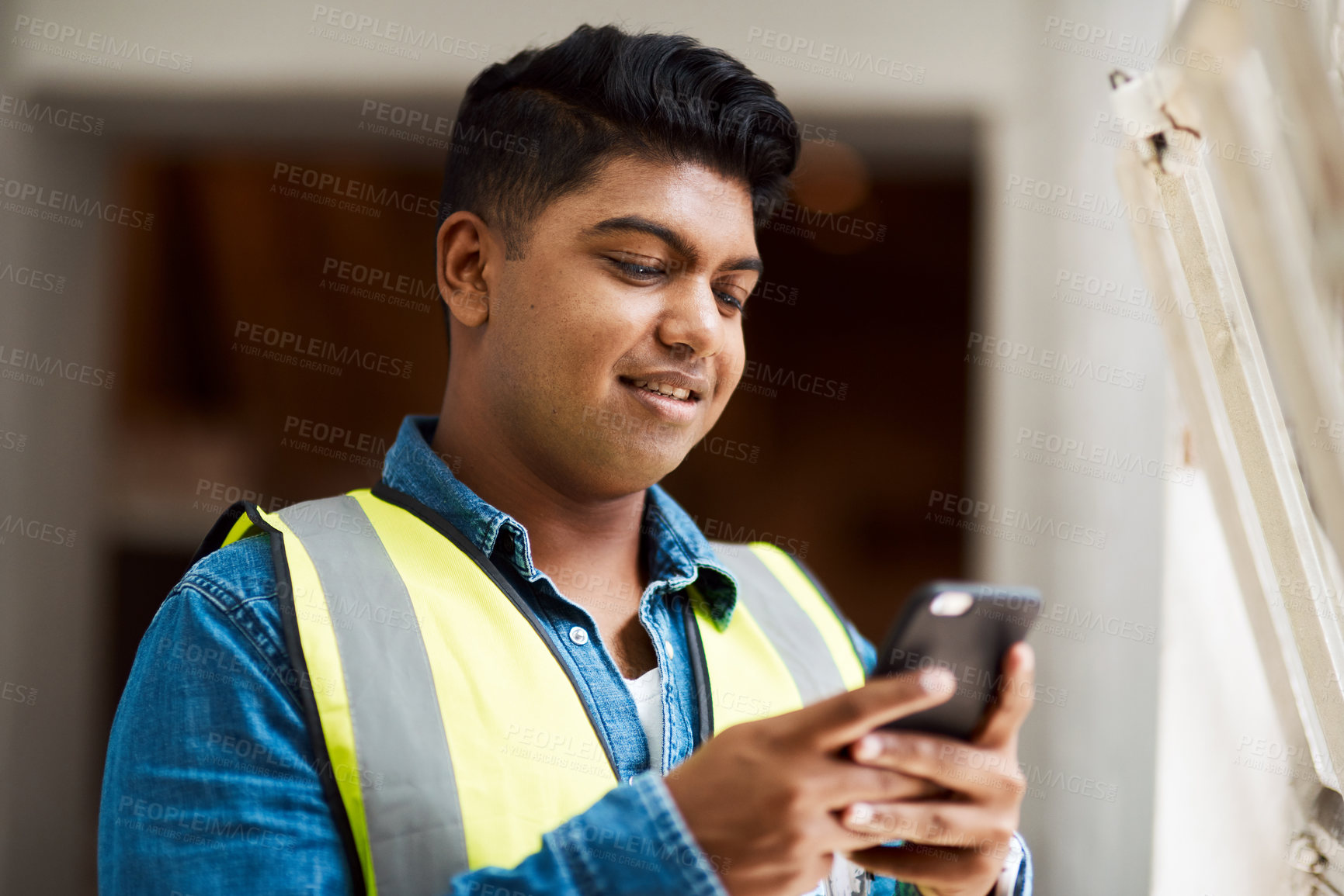 Buy stock photo Shot of a engineer using his cellphone while at work