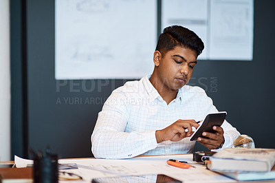 Buy stock photo Shot of a young architect using a calculator while drawing up a building plan