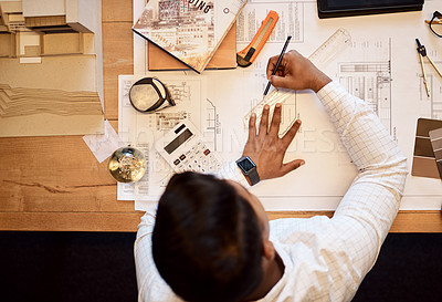 Buy stock photo High angle shot of an architect using a ruler to draw a building plan