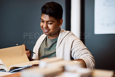 Buy stock photo Shot of a young architect looking through a notebook at his desk in a modern office