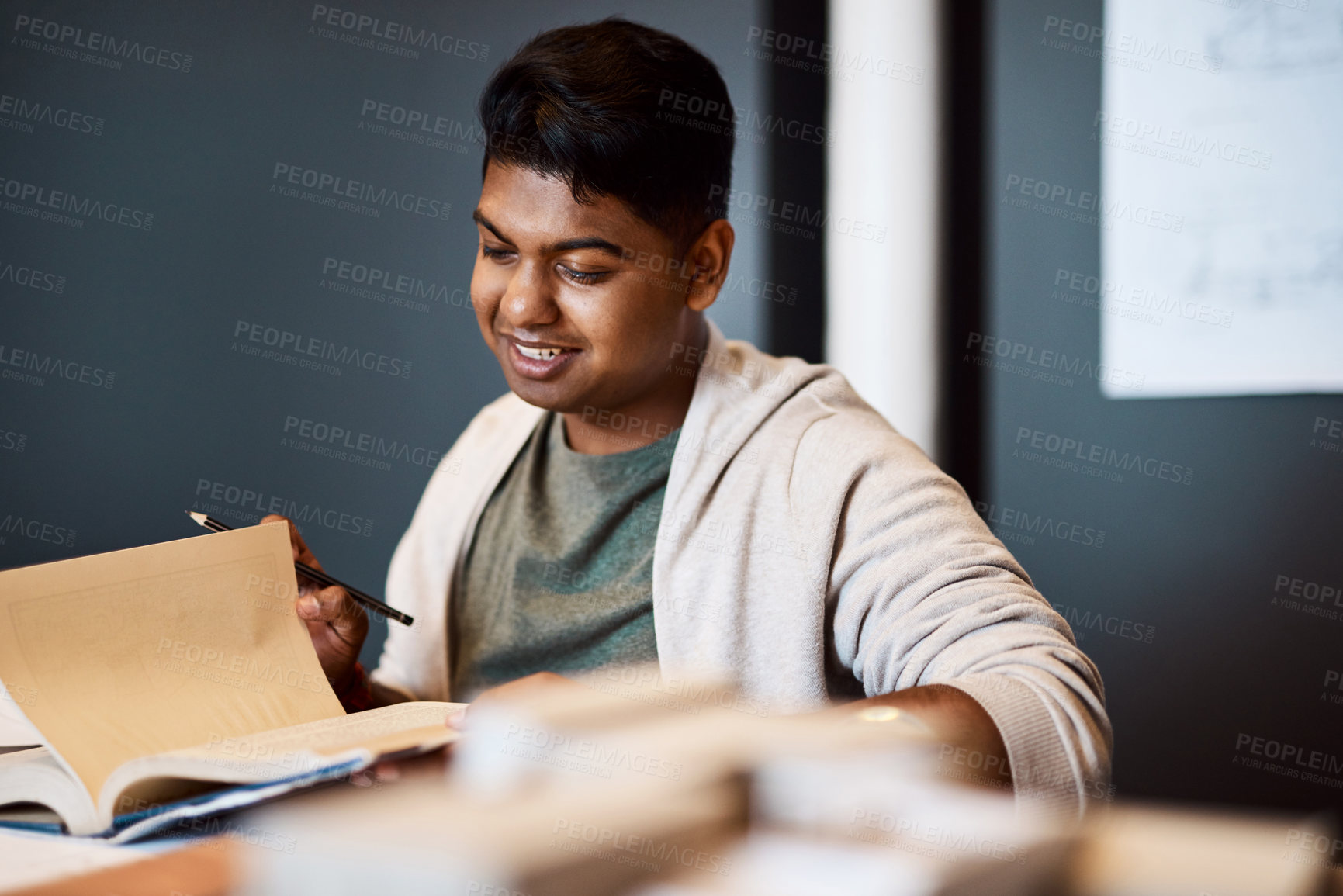 Buy stock photo Shot of a young architect looking through a notebook at his desk in a modern office