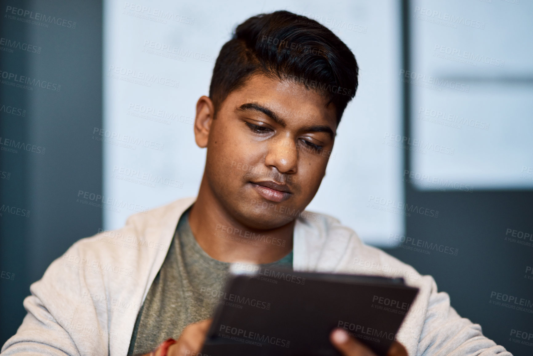 Buy stock photo Shot of a young businessman using a digital tablet in a modern office