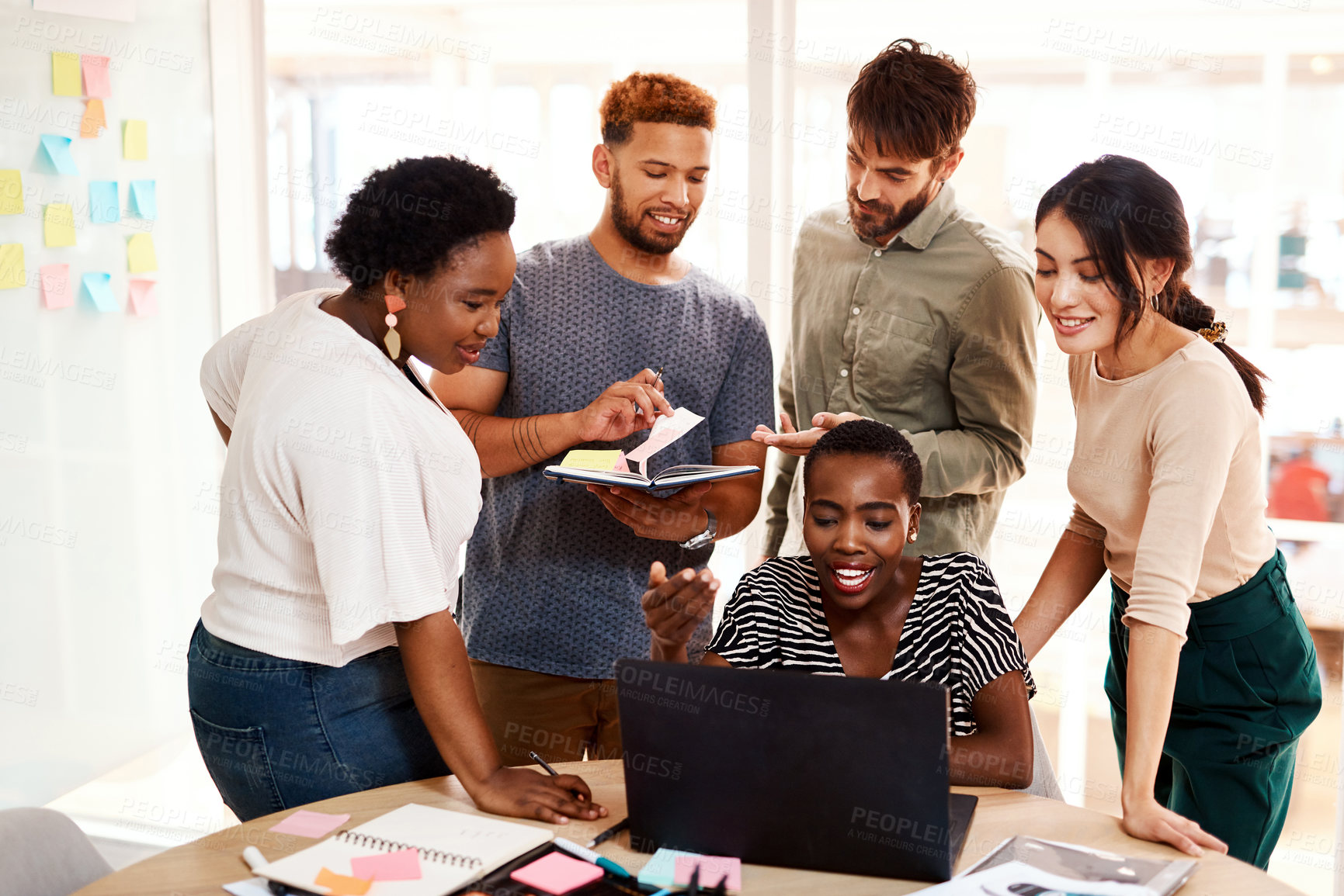 Buy stock photo Shot of a group of young creatives working together on a laptop in an office