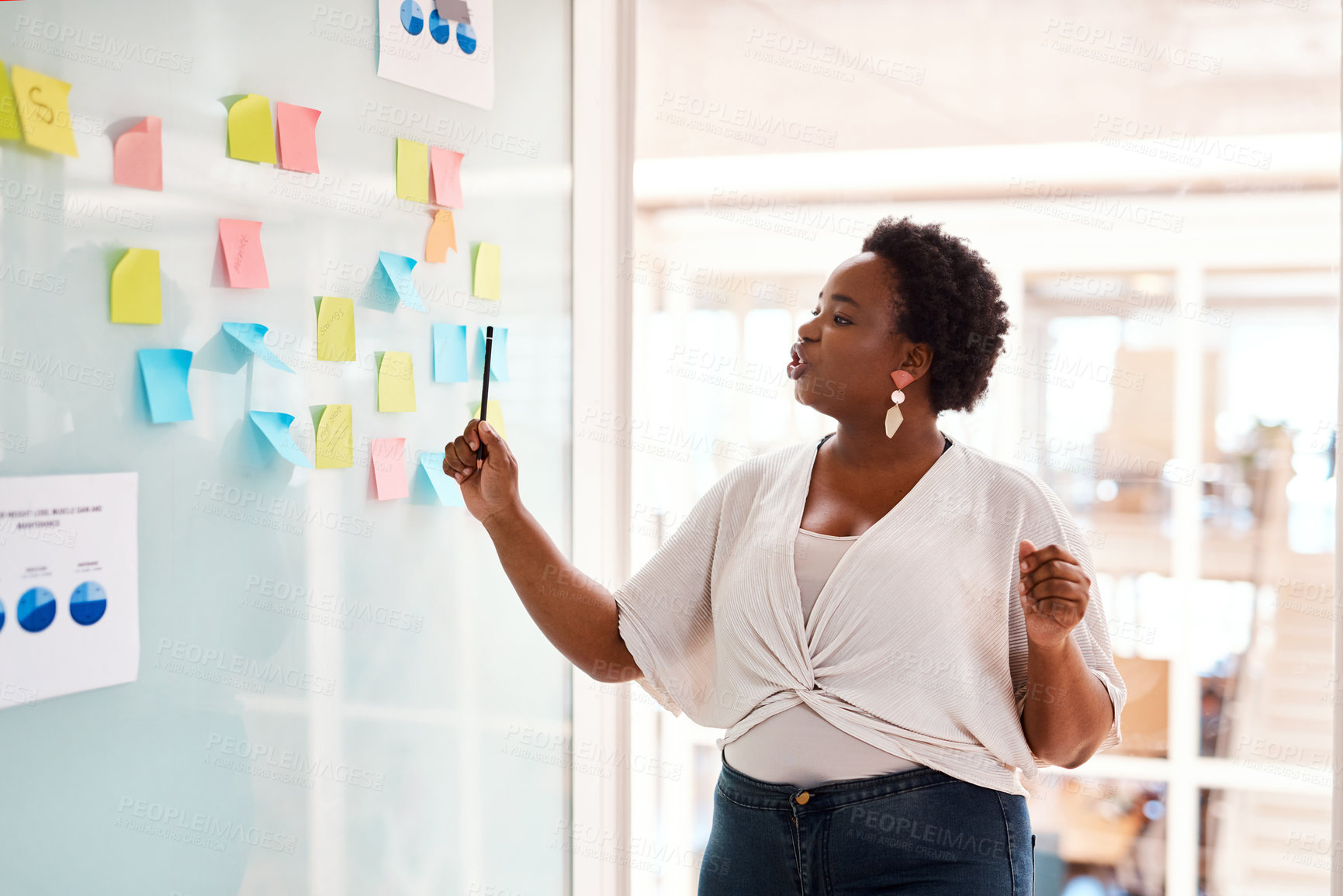 Buy stock photo Shot of a young creative brainstorming with notes on a glass wall in an office