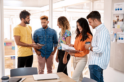 Buy stock photo Cropped shot of a group of young designers having a discussion while standing in the boardroom of their office