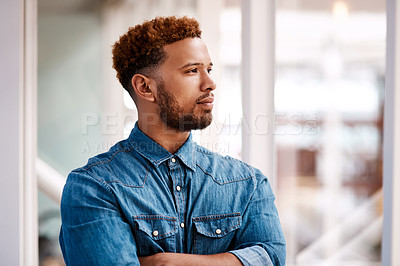 Buy stock photo Cropped shot of a handsome young male designer looking thoughtful while standing with his arms crossed in the office