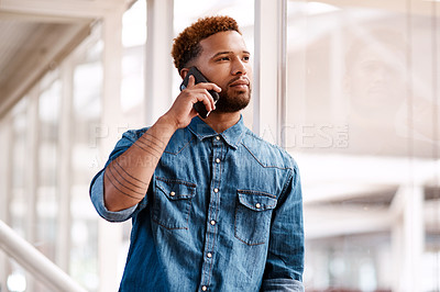 Buy stock photo Cropped shot of a handsome young male designer making a phonecall while standing at at a window in his office