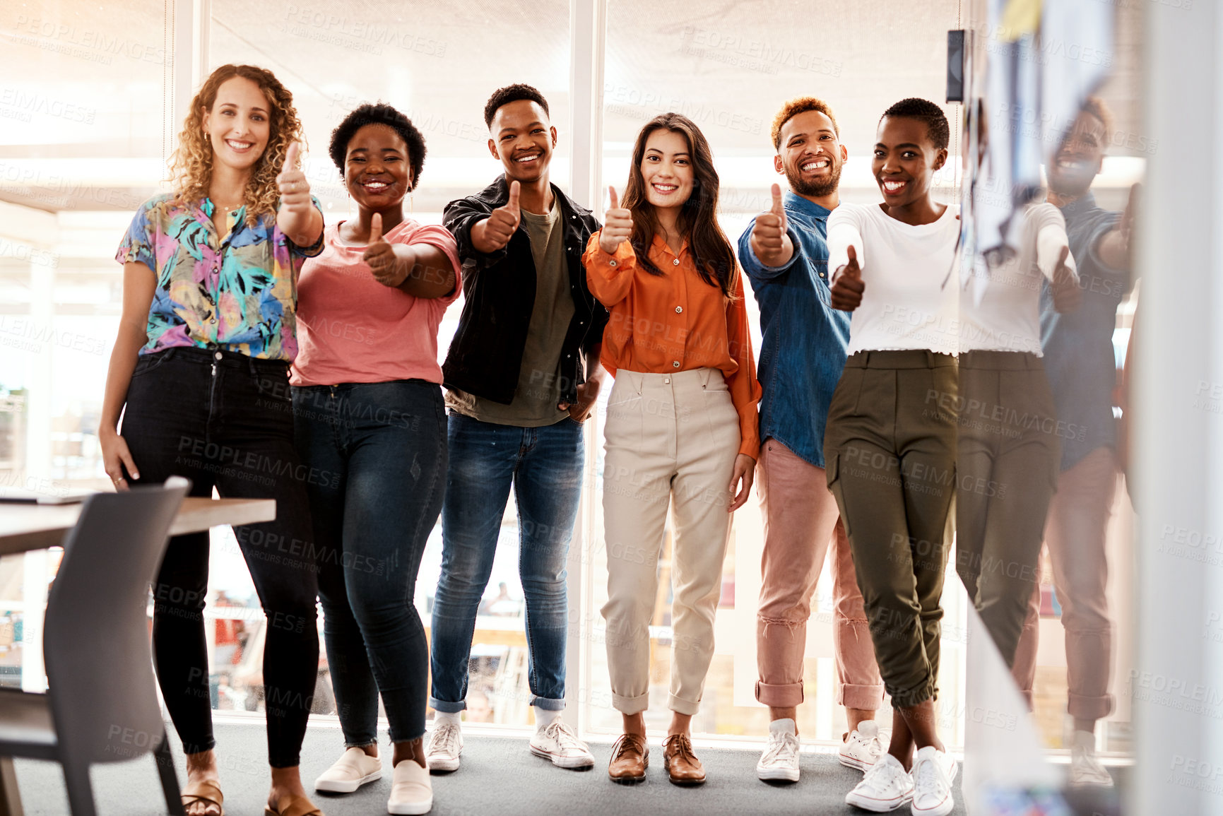 Buy stock photo Full length portrait of a group of young designers giving thumbs up to the camera while standing in the boardroom of their office