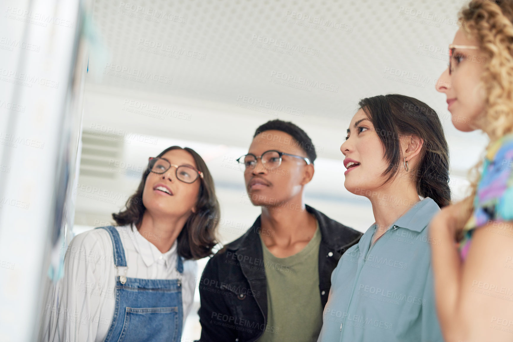 Buy stock photo Shot of a group of businesspeople brainstorming with notes on a wall in an office