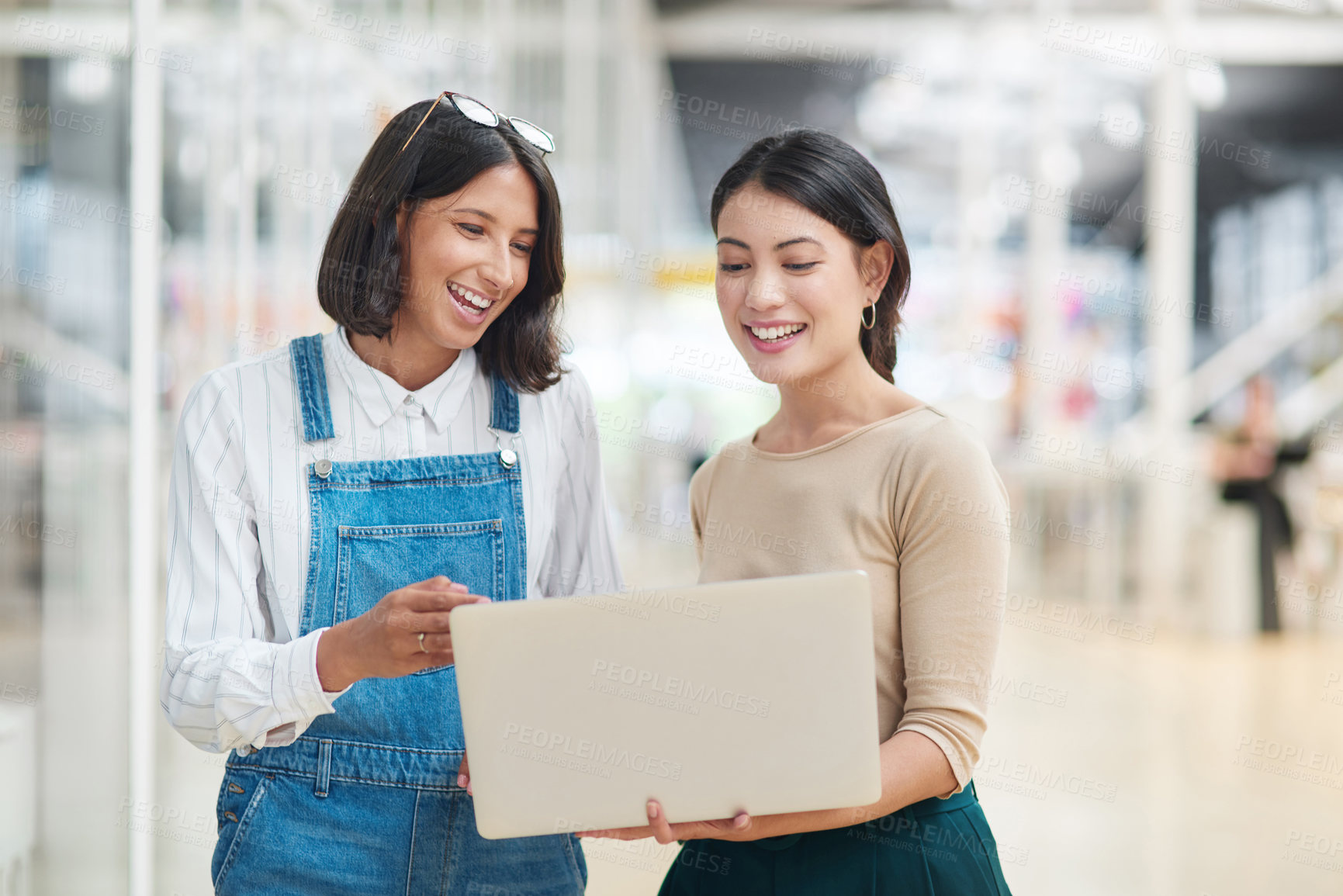 Buy stock photo Shot of two businesswomen working together on a laptop in an office