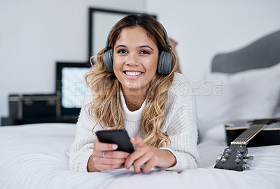 Buy stock photo Woman, phone and headphones with smile on bed with social media marketing for new song release in home. Artist, person and portrait with smartphone, happy and mobile app at apartment in Colombia