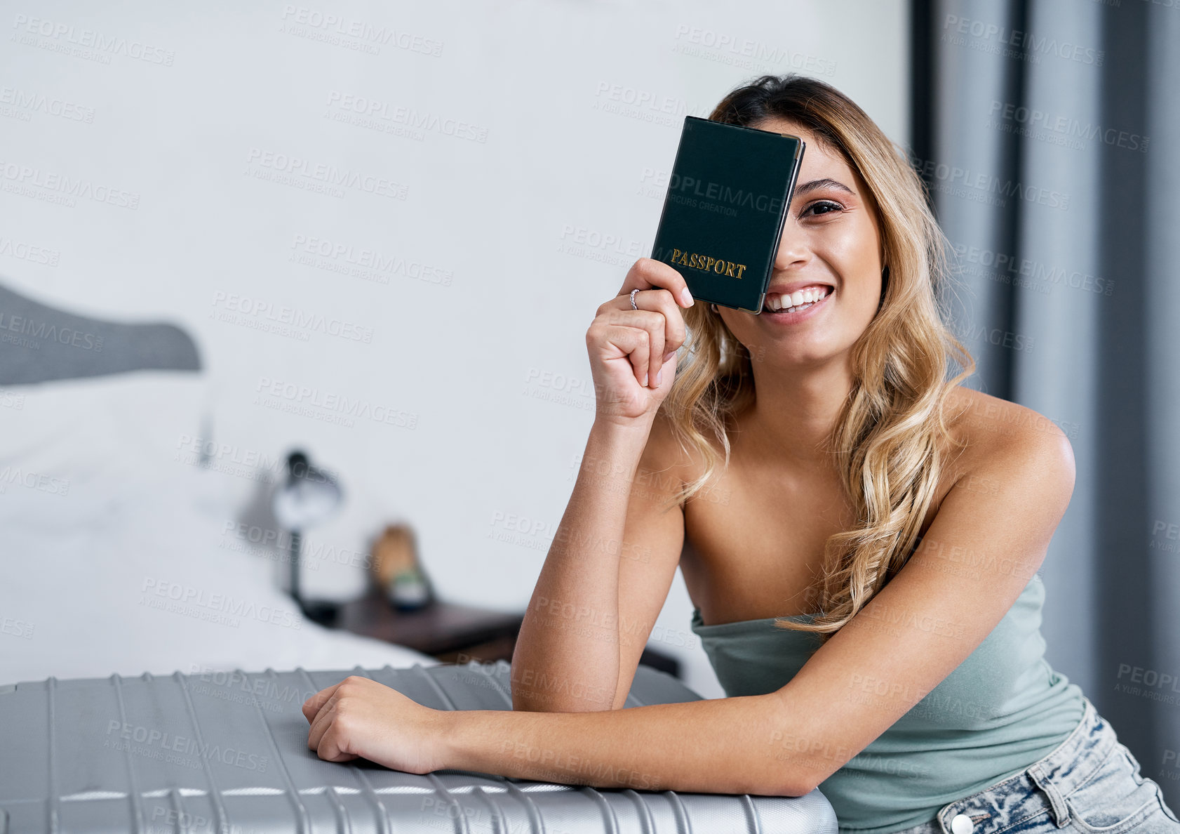 Buy stock photo Cropped shot of a young woman holding up her passport while sitting in her bedroom